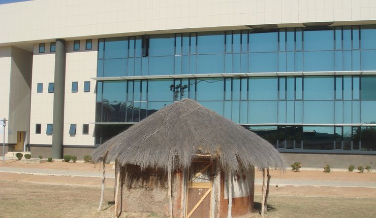 Eine reetgedeckte Hütte direkt vor dem von einer Chinesischen Firma gebauten Glassgebäude der Wirtschaftsfakultät an der Universität Botswana in Gaborone.