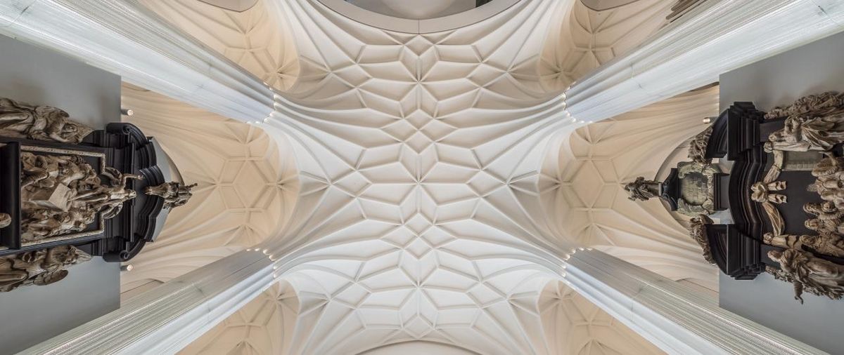 enlarge the image: Architekturfoto: Blick von unten nach oben auf das Gewölbe im Paulinum, welches mit seinen Säulen und der Struktur an der Decke an eine Kirche erinnert.