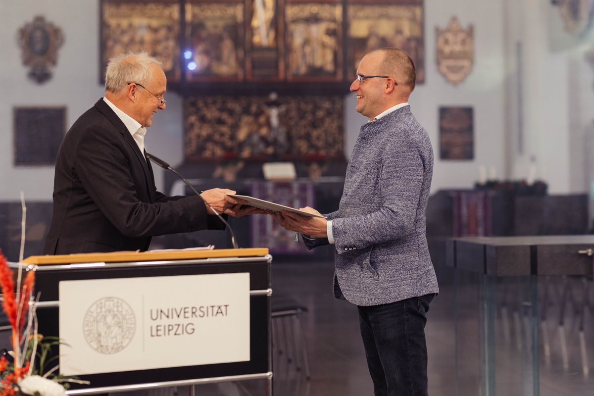 enlarge the image: Prof. Dr. Thomas Lenk steht rechts im Bild. Er überreicht die Urkunde an Prof. Dr. Utz Dornberger und gratuliert ihm. Prof. Dr. Utz Dornberger steht links im Bild