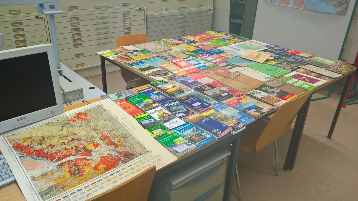 enlarge the image: Verschiedene Exemplare der Kartensammlung der Universität Leipzig auf einem Tisch ausgebreitet.