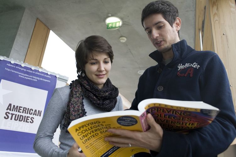 Two students of American Studies looking through a book together