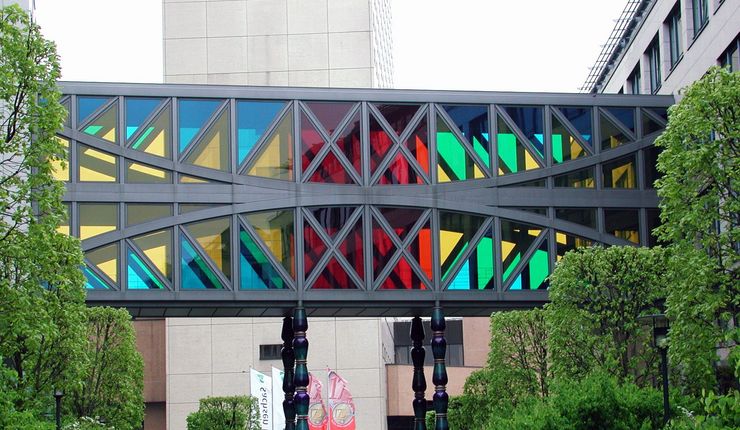 Ein Durchgang im ersten Stockwerk verbindet zwei Gebäude. Die Fenster des Durchgangs haben verschiedene Farben.