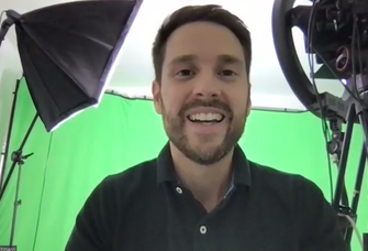 Mirko Drotschmann alias MrWissen2go vor einer grünen Wand mit Kameras und Scheinwerfern im Hintergrund