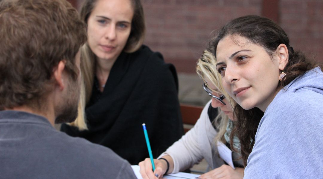 Three young people sitting at a table talking to each other