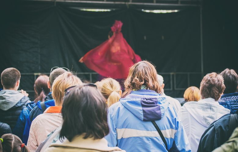 Zu sehen sind Zuschauer vor einer Freiluft-Theaterbühne.