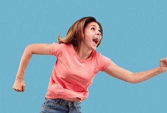Eine junge Frau springt vor Freude in die Luft.