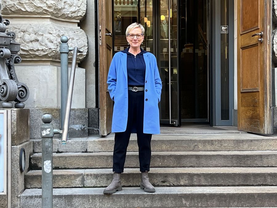zur Vergrößerungsansicht des Bildes: Charlotte Bauer steht auf der Treppe am Eingang zur Bibliotheca Albertina.