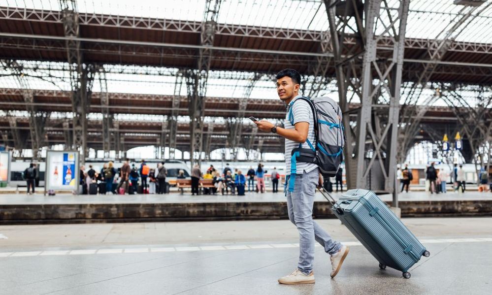 zur Vergrößerungsansicht des Bildes: Mann seitlich zu sehen, wie er auf Bahnsteig läuft und dabei einen Koffer zieht