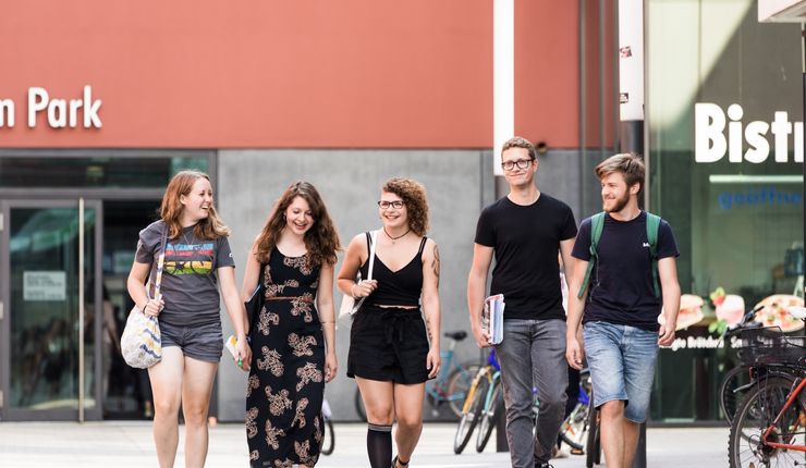 Studierende gehen nebeneinander auf dem Campusgelände