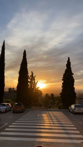Farbfoto: Abendufnahme eines Zebrastreifens neben parkenden Autos. Aufnahme gegen die goldene Sonne am Horizont 