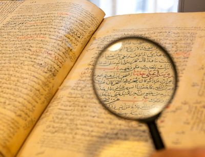 Eine Lupe wird auf ein arabisches Buch gehalten