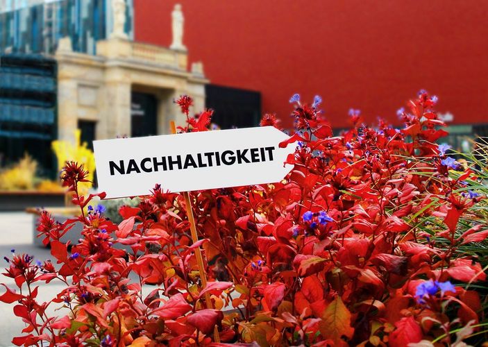 Zu sehen ist das Leibniz-Forum der Universität Leipzig, im Vordergrund ein Schild mit der Aufschrift "Nachhaltigkeit".