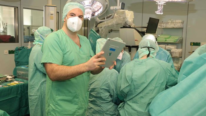 Handchirurg Dr. Nick Spindler mit einem Tablet in der Hand im OP-Saal