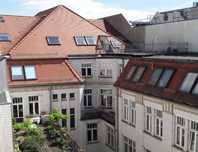 Blick auf den Innenhof der Hainstraße 11 bei Sonnenschein: rot gedeckte Mehrfamilienhäuser mit weißer Fassade und teilweise begrünten Dachterrassen.