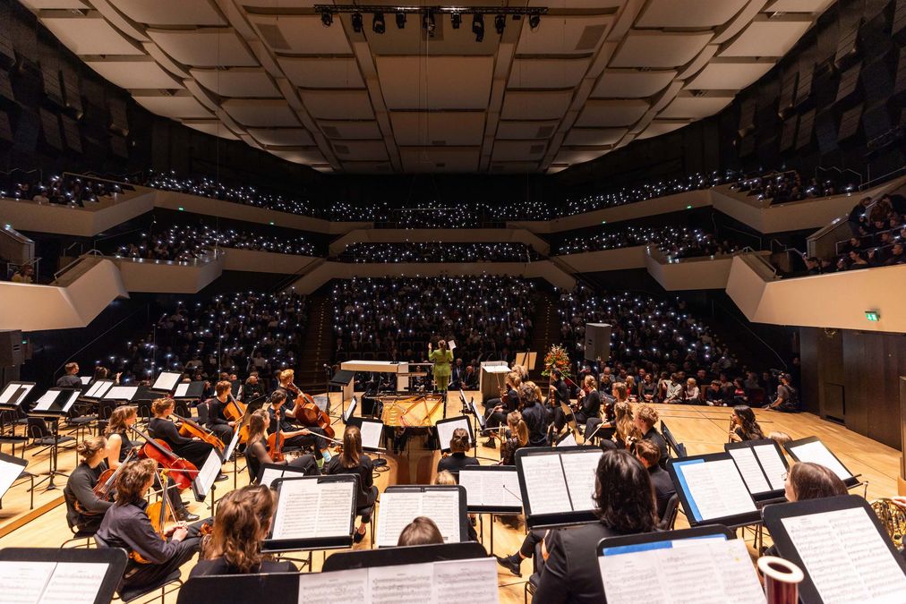 zur Vergrößerungsansicht des Bildes: Publikum im Gewandhaus. Die Menschen erzeugen eine Lichtwolke mit ihren Smartphones.