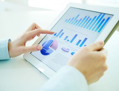 Frau hält Tablet, auf dem Diagramme abgebildet sind.