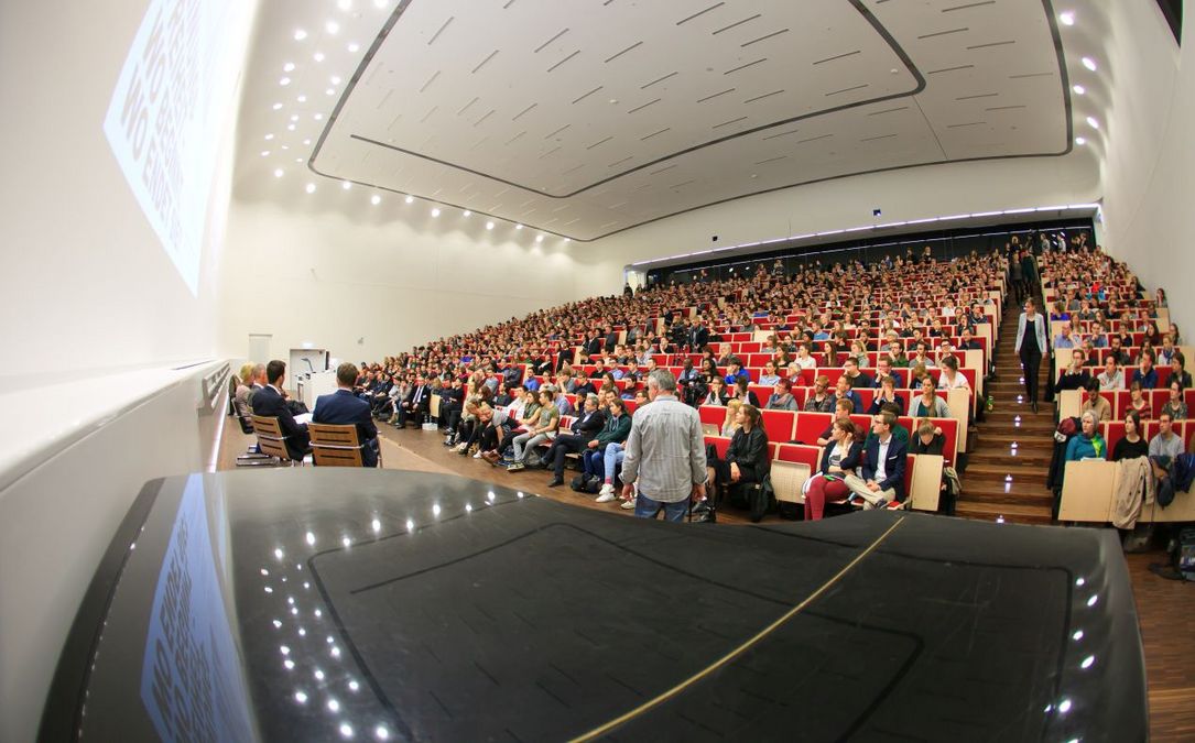 zur Vergrößerungsansicht des Bildes: Foto: voller Hörsaal der dem podium auf der Bühne folgt