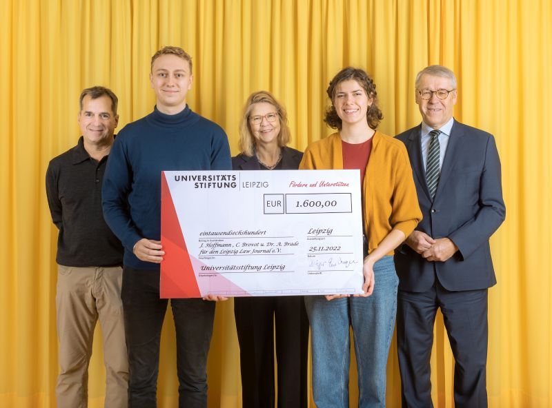 zur Vergrößerungsansicht des Bildes: Farbfoto: Prof. Dr. Birgit Dräger, Dr. Hubert Temmeyer und Prof. Dr. Harald Krautscheid von der Universitätsstiftung überreichen den symbolischen Scheck an die Fördermittelempfänger:innen Jakob Hoffmann und Celine Brovot für den Leipzig Law Journal e.V.