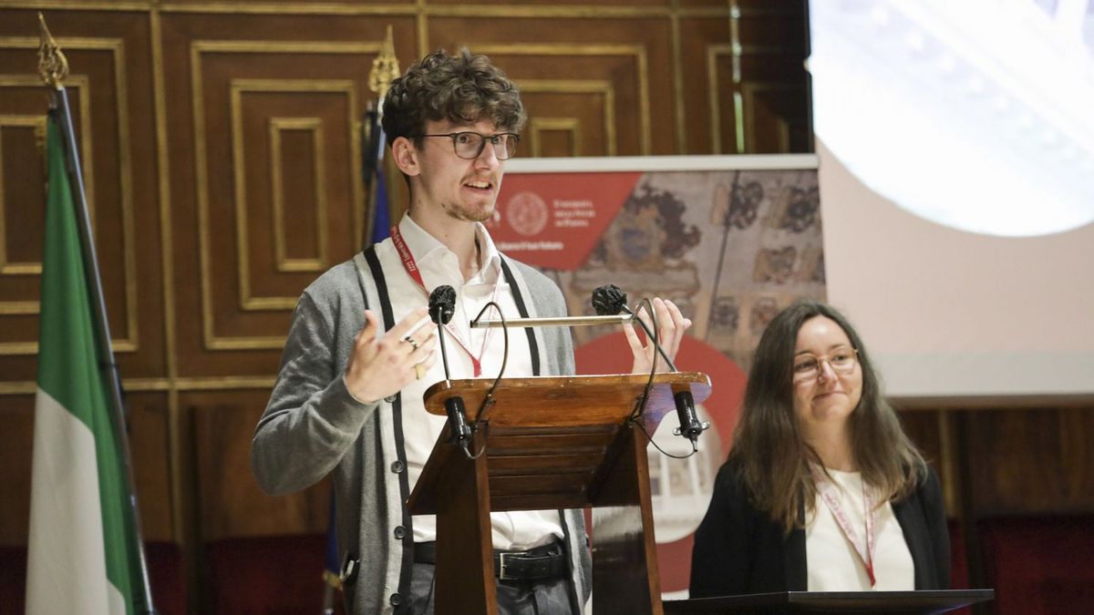 enlarge the image: Student representative Benedikt Grothe gives a speech at the Arqus Annual Assembly in Padua 2022 standing behind a podium