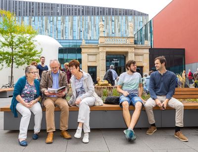 Studierende der Seniorenakademie und junge Studierende sitzen auf dem Campus