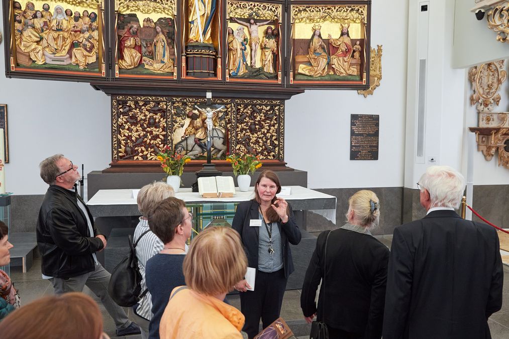 zur Vergrößerungsansicht des Bildes: Frau Dr. Tübbecke von der Kustodie steht vor dem Altar und führt die Gäste durch den Altarbereich im Paulinum 