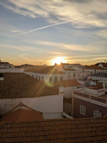 Farbfoto: Abendaufnahme gegen die Sonne mit Blick auf die roten Dächer von weißen Häusern 