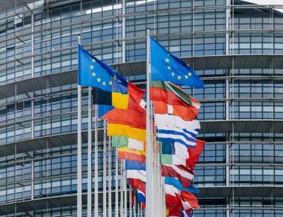 Farbfoto vom Europaparlament mit verschiedenen Nationalflaggen