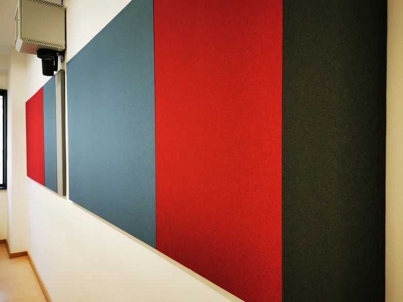 Zu sehen sind graue und rote Wandplatten, die mit grauem und roten Stoff bespannt sind.