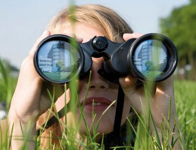 Kind schaut durch Fernglas auf die Universität