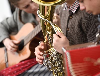 Zu sehen sind drei Musiker in volkstümlicher Kleidung. Sie spielen Gitarre, Tuba und Akkordeon.