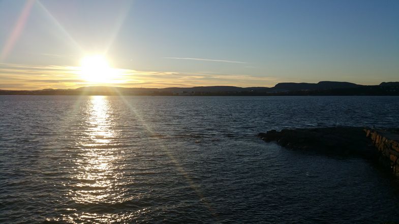 Das Bild zeigt den Strand Paradisbukta in Norwegen mit einem Sonnenuntergang.