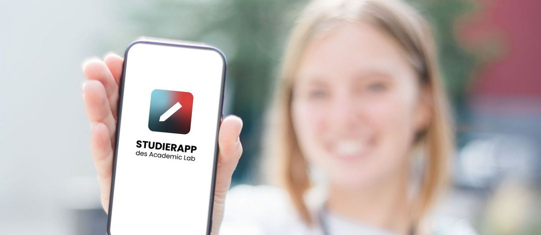 Eine Studentin hält ein Smartphone mit geöffneter Studierapp. Foto: Academic Lab