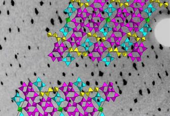 Die Grafik zeigt im Hintergrund einen Ausschnitt der Messdaten, ein Röntgenbeugungsdiagramm der Phosphoroxidnitride. Im Vordergrund sind Ausschnitte aus der Kristallstruktur zu sehen. Es handelt sich um Netzwerke aus Tetraedern, in deren Zentrum jeweils Phosphor-Atome sind.