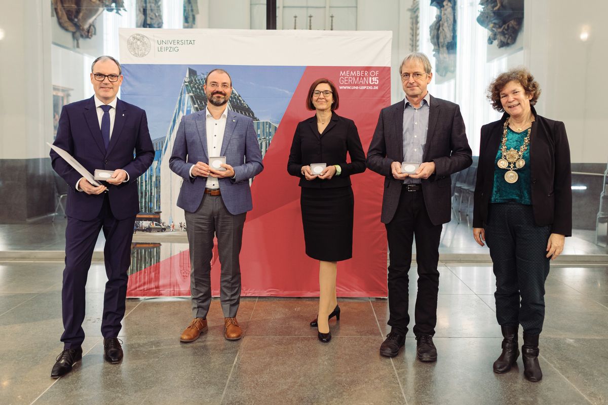 zur Vergrößerungsansicht des Bildes: Preisträger der Universitätsmedaille posieren im Paulinum vor einem Banner der Universität zusammen mit der Rektorin Beate Schücking