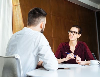 Zwei Personen sitzen im beruflichen Umfeld an einem Tisch und sind im Gespräch