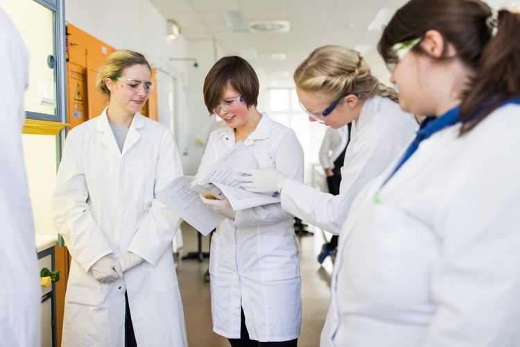 Studentinnen der Biochemie stehen im Kreis zusammen und schauen sich gemeinsam Laborergebnisse an, Foto: Christian Hüller