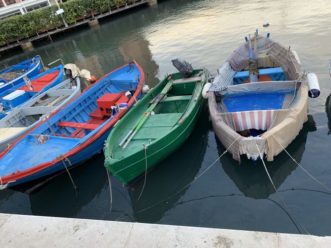 Farbfoto: Nahaufnahme von sechs bunten Fischerbooten die im Wasser nebeneinander stehen 