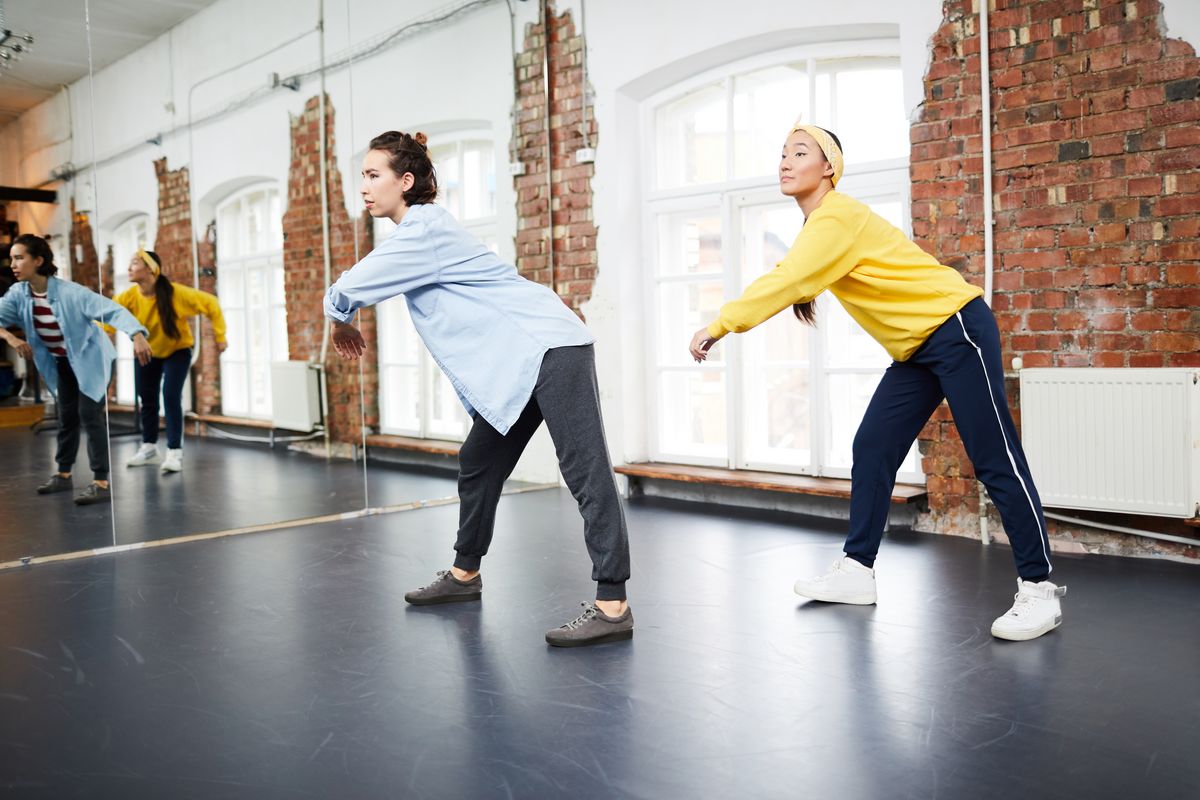 zur Vergrößerungsansicht des Bildes: Auf dem Bild sieht man zwei jugendliche Mädchen, die in einem Tanzstudio vor Spiegeln eine Choreographie einüben.