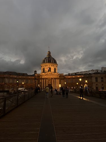 Pont d\'art in der Dämmerung von Scheinwerfern beleuchtet, Blick von einer Brücke mit Menschen, wolkenverhangener Himmel