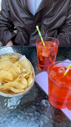 Farbfoto: Aufnahme von zwei Gläsern mit roter Flüssigkeit und einem Korb mit Chips auf einem Tisch