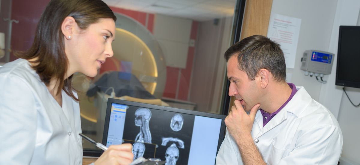 Two physicians examining results of an MRI scan displayed on the monitor