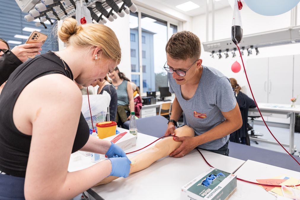 zur Vergrößerungsansicht des Bildes: Eine Frau, die an einem künstlichen Arm versucht einen Katheder zu setzen.