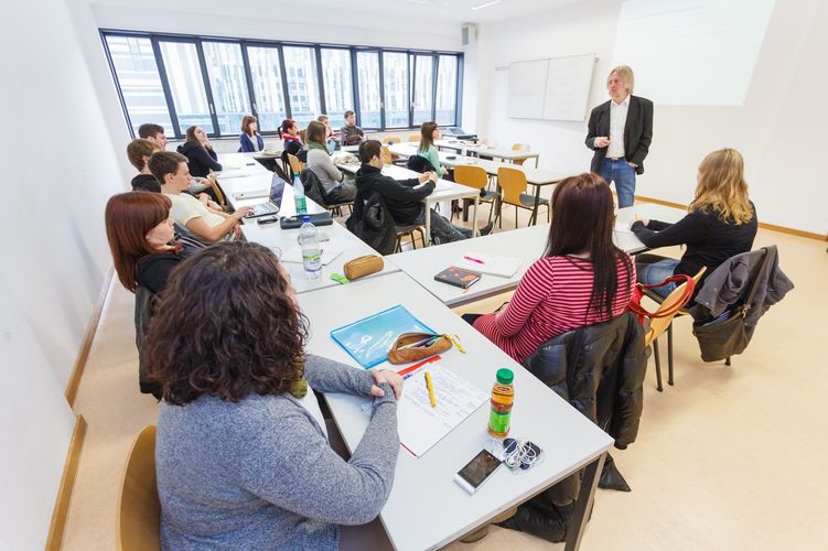 Studierende sitzen in einem Seminarraum und hören dem Dozenten zu, Foto: Christian Hüller 
