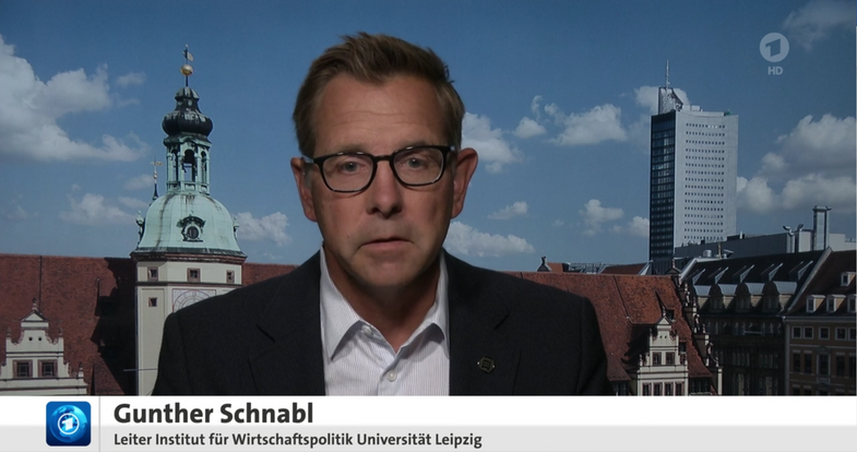 Standbild eines Fernsehbeitrags mit Günter Schnabl, Leiter des Instituts für Wirtschaftspolitik der Universität Leipzig, vor der Siluette Leipzigs