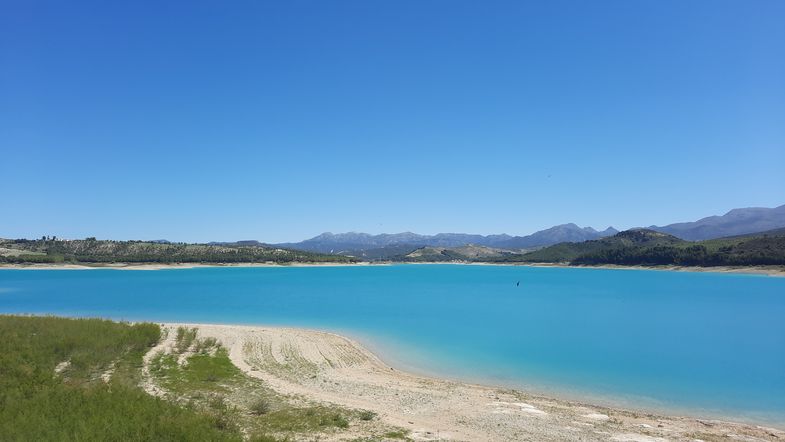 Farbfoto: Aufnahme eines hellblauen Sees und Bergen im Hintergrund