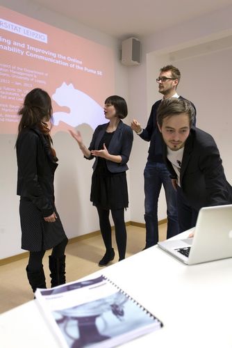 Vier Studierende stehen im Seminarraum. Hinter ihnen ist eine Präsentation an die Wand projiziert, Foto: Christian Hüller 
