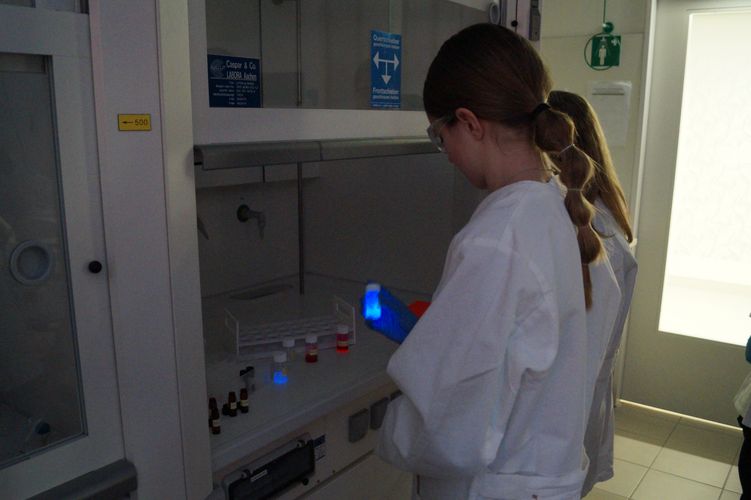 Girl holding a vial with a glowing liquid (Photo: Toshiki Wulf / Leipzig University, RTG 2721)