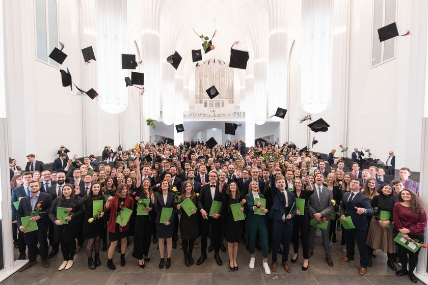 Die Absolventen und Absolventinnen stehen zum Gruppenfoto zusammen und schmeißen ihre schwarzen Hüte in die Luft, Foto: Christian Hüller