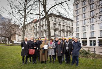 In einem Park steht eine Gruppe von Menschen vor Bäumen