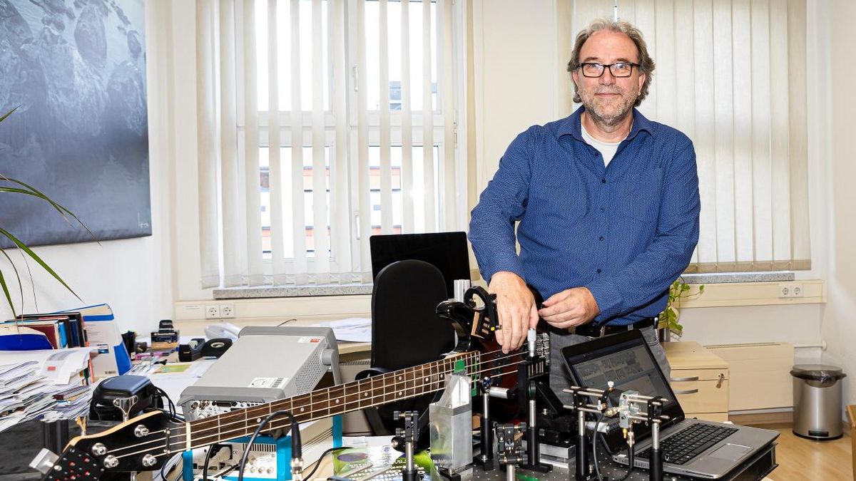 Prof. Dr. Jan Meijer mit einem roten Diamanten und einer E-Gitarre und dem Versuchsaufbau